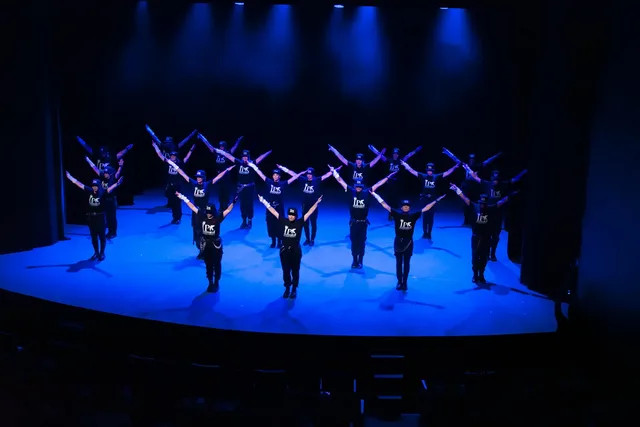 La compañía Jackson Project bailando en formación bajo las luces azules del teatro